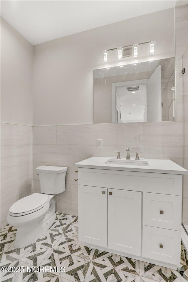 bathroom featuring vanity, toilet, tile patterned flooring, and tile walls