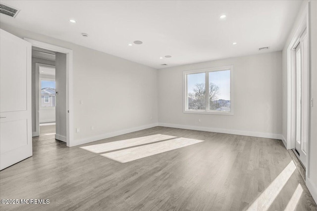 empty room with plenty of natural light and light hardwood / wood-style flooring