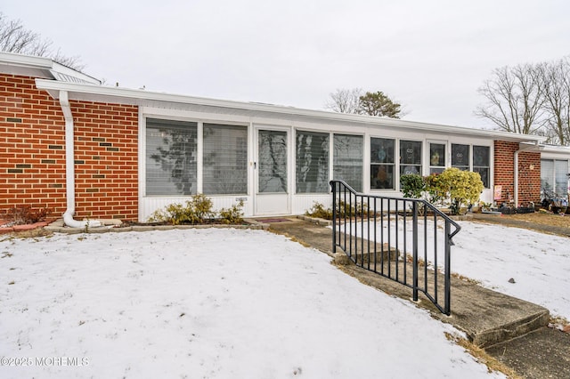 snow covered property featuring a sunroom