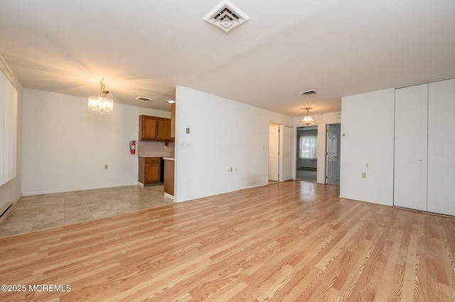 unfurnished living room with an inviting chandelier and light wood-type flooring