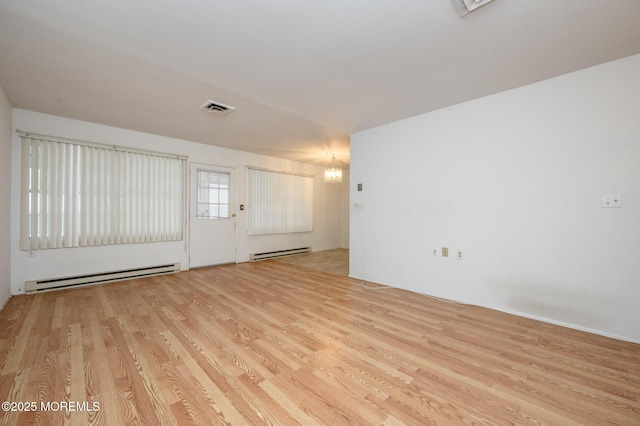 spare room with a baseboard radiator, a chandelier, and light wood-type flooring