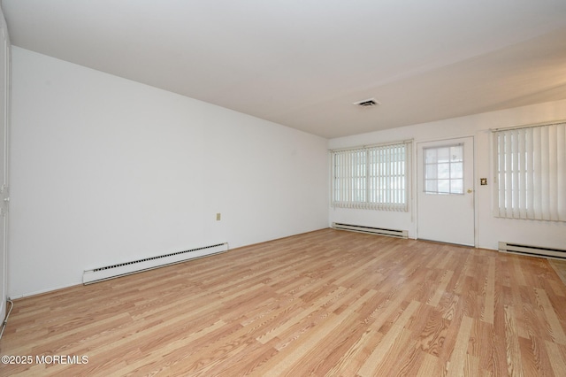 unfurnished room featuring a baseboard heating unit and light hardwood / wood-style floors