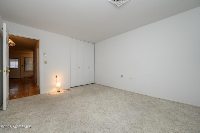 unfurnished bedroom featuring light colored carpet and a closet