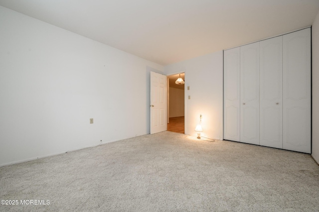 unfurnished bedroom featuring light colored carpet and a closet