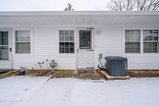 snow covered property entrance with central AC unit