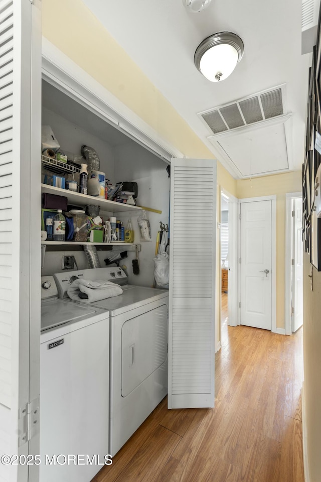 clothes washing area with washing machine and dryer and light wood-type flooring