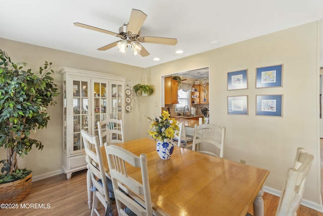 dining space with sink, light hardwood / wood-style flooring, and ceiling fan