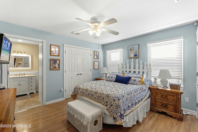 bedroom with connected bathroom, light hardwood / wood-style flooring, a closet, and ceiling fan