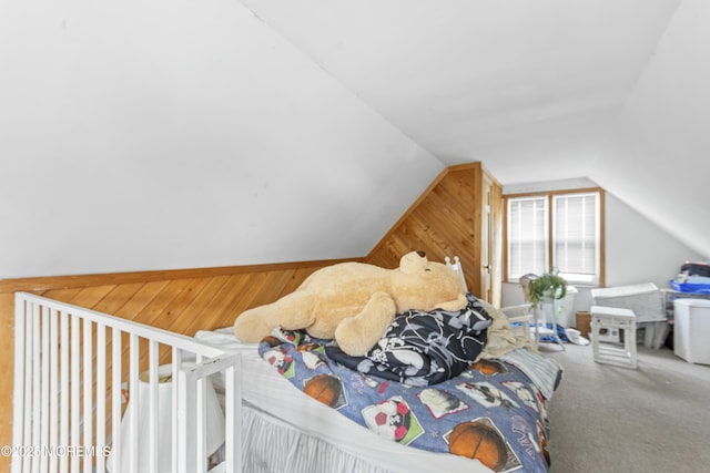 carpeted bedroom with lofted ceiling and wooden walls