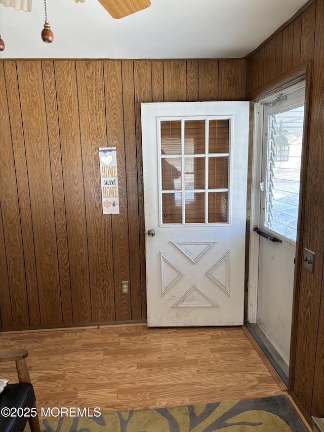 doorway to outside with light hardwood / wood-style flooring, wooden walls, and a healthy amount of sunlight