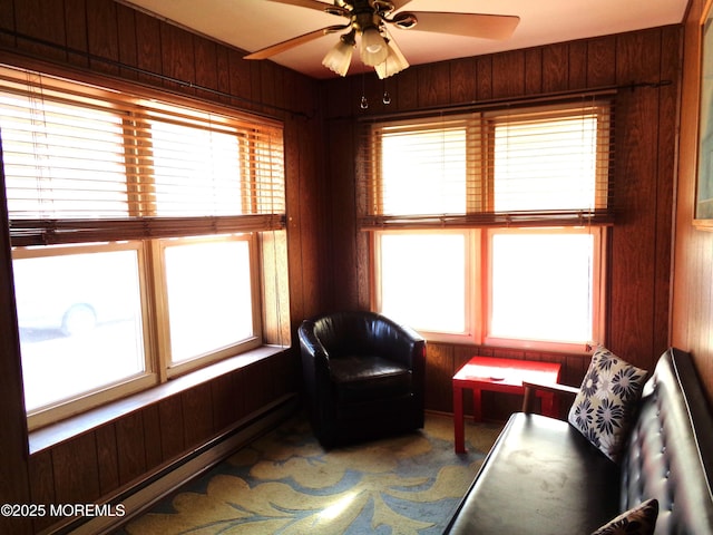 living area with ceiling fan and wooden walls