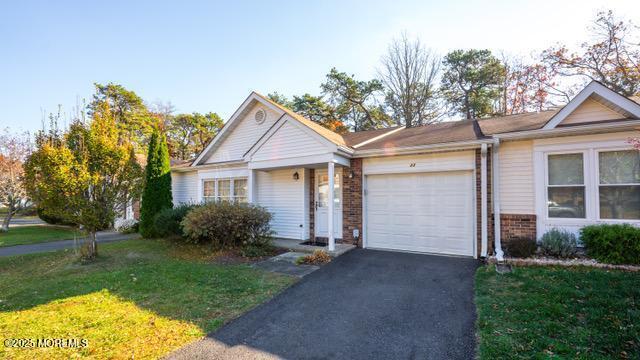 view of front of house with a front lawn, brick siding, driveway, and an attached garage