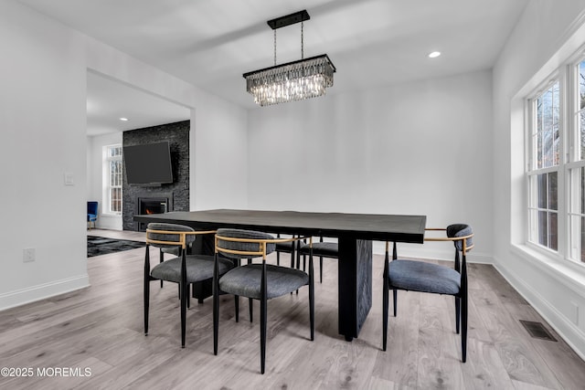 dining space featuring a fireplace and light hardwood / wood-style flooring