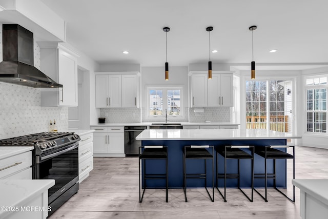 kitchen with sink, white cabinetry, stainless steel range with gas stovetop, black dishwasher, and wall chimney exhaust hood