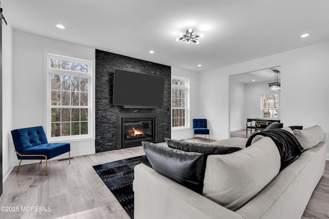 living room with a barn door, a large fireplace, a notable chandelier, and light hardwood / wood-style floors