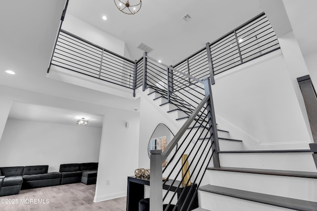 staircase featuring a towering ceiling and wood-type flooring