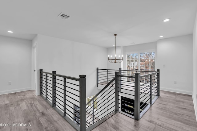 stairs featuring hardwood / wood-style flooring and a notable chandelier