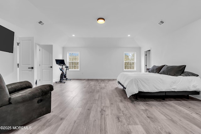 bedroom featuring multiple windows, lofted ceiling, and light hardwood / wood-style floors