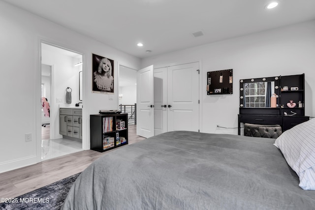 bedroom featuring light hardwood / wood-style floors, a closet, and ensuite bathroom