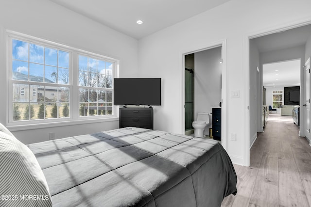 bedroom with light hardwood / wood-style floors and ensuite bath