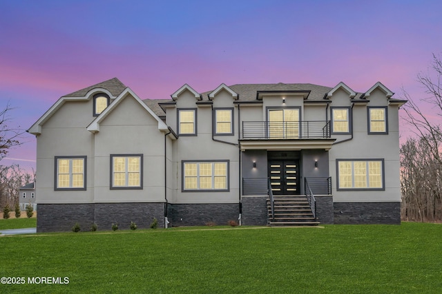 view of front of home with french doors, a balcony, and a yard