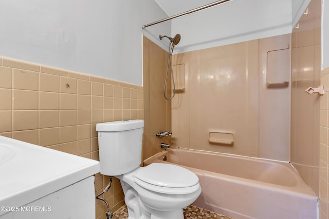 bathroom with tile walls, shower / bathing tub combination, and toilet