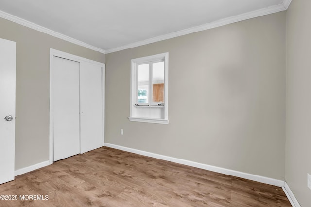 unfurnished bedroom featuring ornamental molding, a closet, and light hardwood / wood-style flooring