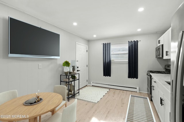 kitchen featuring appliances with stainless steel finishes, a baseboard heating unit, light stone countertops, light hardwood / wood-style floors, and white cabinets