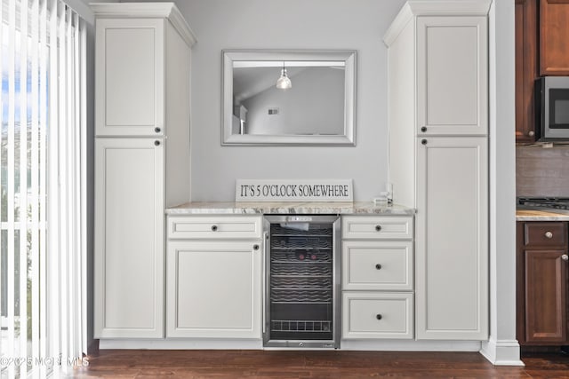 bar with white cabinetry, light stone countertops, dark hardwood / wood-style floors, and beverage cooler