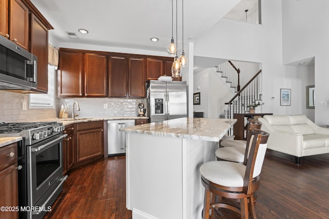 kitchen featuring sink, dark wood-type flooring, a breakfast bar, stainless steel appliances, and a kitchen island