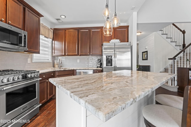 kitchen with light stone countertops, a kitchen breakfast bar, a center island, and appliances with stainless steel finishes