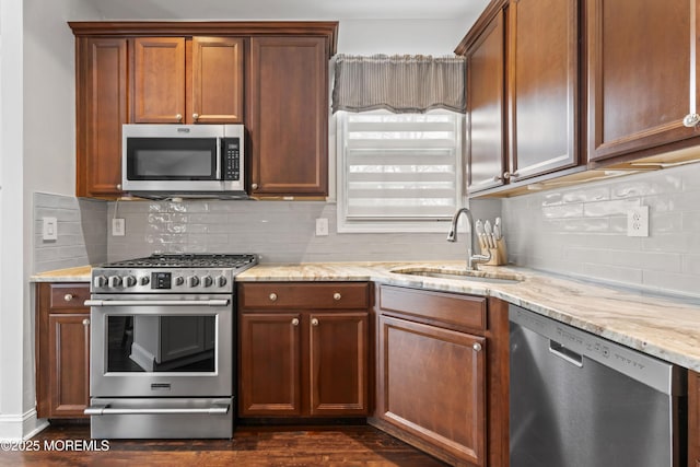 kitchen with sink, backsplash, dark hardwood / wood-style flooring, stainless steel appliances, and light stone countertops