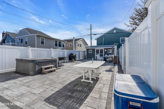 view of patio with area for grilling, a hot tub, and an outdoor structure