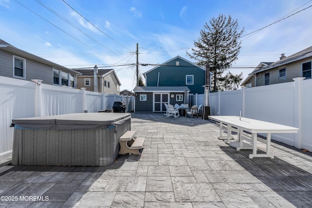 view of patio / terrace featuring a hot tub and a shed