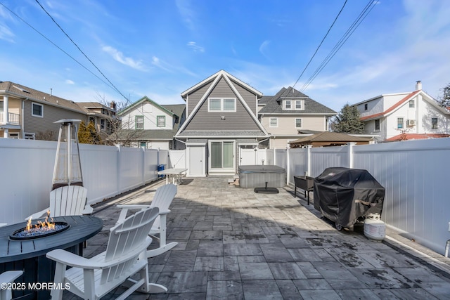 back of house featuring a hot tub, a patio, and an outdoor fire pit