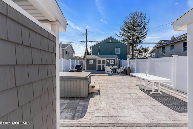 view of patio with a hot tub and an outbuilding