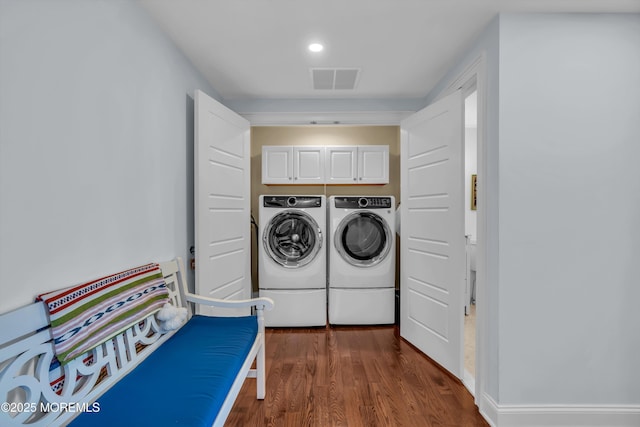 laundry room featuring separate washer and dryer, dark wood-type flooring, and cabinets