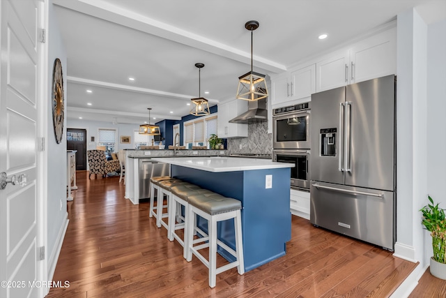 kitchen with a breakfast bar, hanging light fixtures, appliances with stainless steel finishes, a kitchen island, and white cabinets