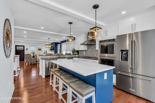 kitchen featuring a kitchen bar, decorative light fixtures, white cabinets, and appliances with stainless steel finishes