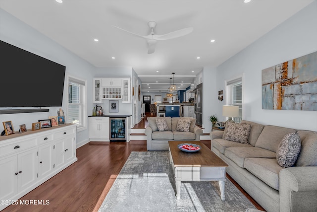 living room with wine cooler, ceiling fan, bar area, and dark hardwood / wood-style floors