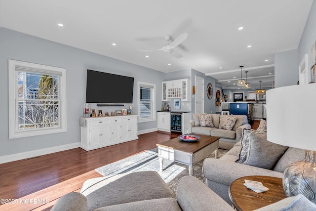 living room with ceiling fan, bar, beverage cooler, and hardwood / wood-style floors