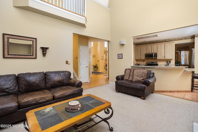 living room featuring a towering ceiling and light colored carpet