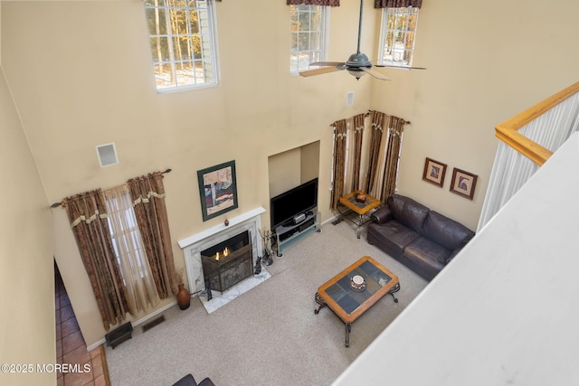 living room featuring a towering ceiling, ceiling fan, and carpet flooring