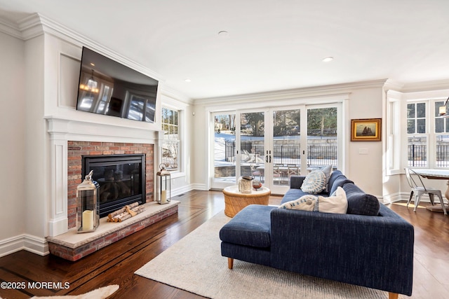 living room with a brick fireplace, crown molding, and dark wood-type flooring