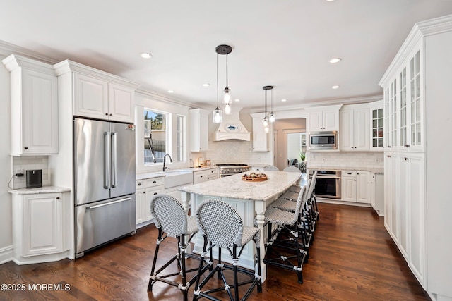 kitchen featuring a kitchen island, high quality appliances, white cabinets, custom exhaust hood, and ornamental molding