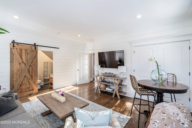 living room with dark hardwood / wood-style floors, a barn door, and wood walls