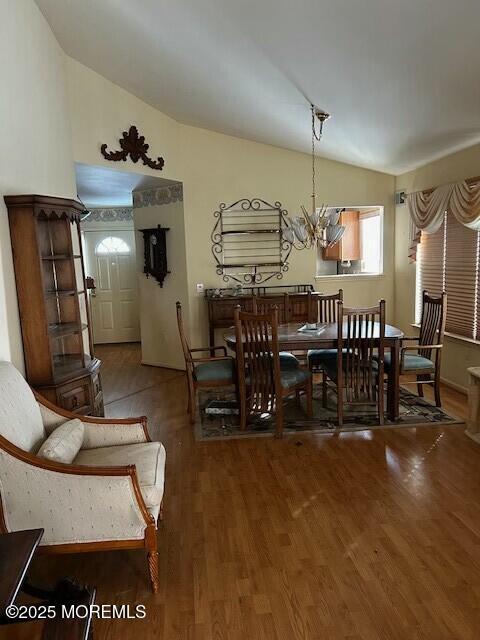 dining area featuring vaulted ceiling, wood-type flooring, and a notable chandelier