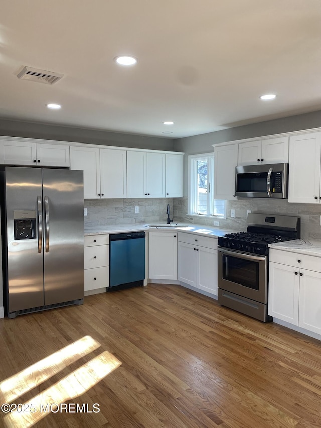 kitchen featuring wood-type flooring, white cabinets, and appliances with stainless steel finishes