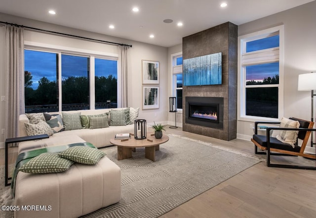 living room with a tiled fireplace and light hardwood / wood-style floors