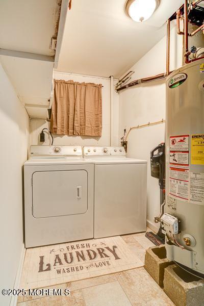 washroom with water heater and independent washer and dryer